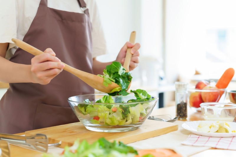 femeie care gateste o salata cu ingrediente proaspete