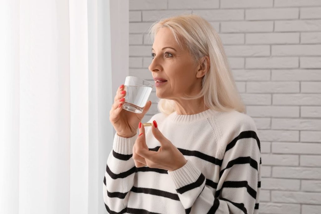 femeie care administrează un supliment pentru a susține sănătatea ficatului