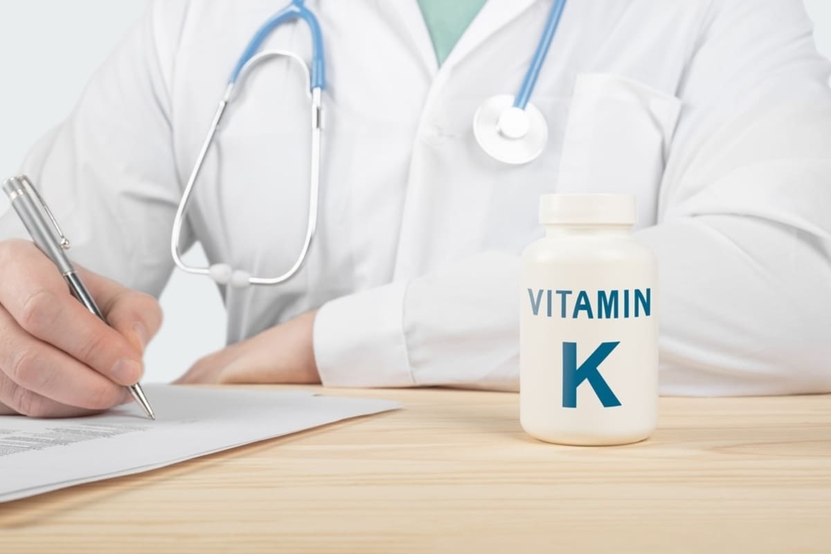 medic care scrie o rețetă și o cutie de vitamina K în prim-plan